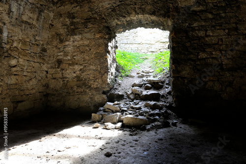 Stone archway leading from dark ruin to bright green overgrown path