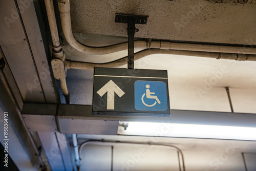 Accessibility sign with wheelchair symbol and upward arrow inside Broadway Lafayette Street subway station in Manhattan. Underground New York City metro environment showing public transportation and