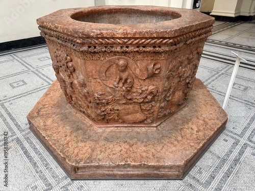 Ancient Engraved Stone Basin: Large ceremonial vessel made of orange and red stone with intricate historical carvings and a well-like structure.
