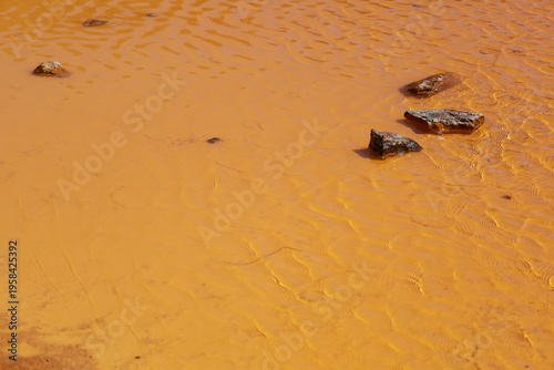 Pit lake with orange hues due to oxidation and mining waste