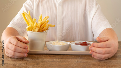 Food background with potato chips, mayonnaise and ketchup in the hands of a child. Tasty snack for kids.