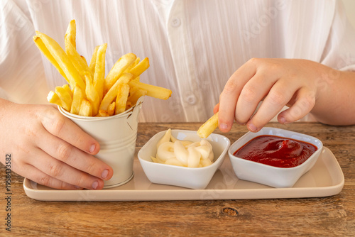Food background with potato chips in the hands of a child. Tasty snack for kids.
