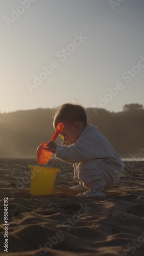 Baby Playing with a Bucket and Shovel on the Beach at Sunset