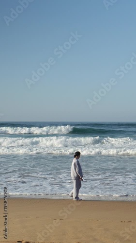Woman in a Tracksuit Walking Along the Ocean Shore on a Sunny Day