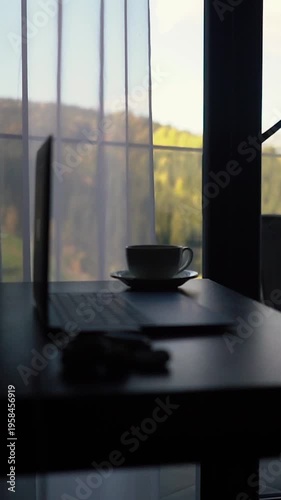 A cup of morning coffee on the table in a hotel room during breakfast. A businessman working and spending his morning meeting on a laptop while traveling on vacation. A trip to the mountains.