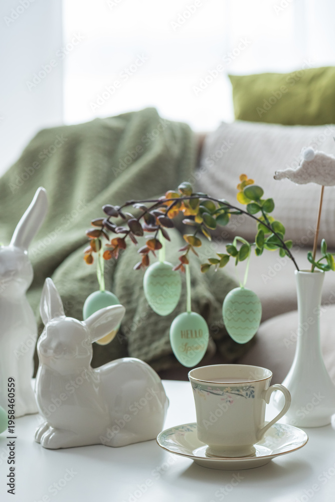Naklejka premium Spring Table Decor with Bunny Figurines, Hanging Eggs and Floral Cup of Coffee