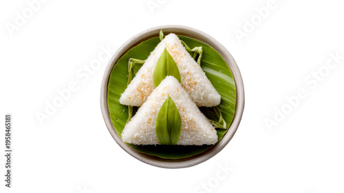 Two triangular sticky rice cakes with coconut flakes on a banana leaf in a bowl isolated on transparent background
