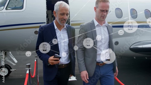 Animation of network of digital icons over two caucasian businessmen walking at airport