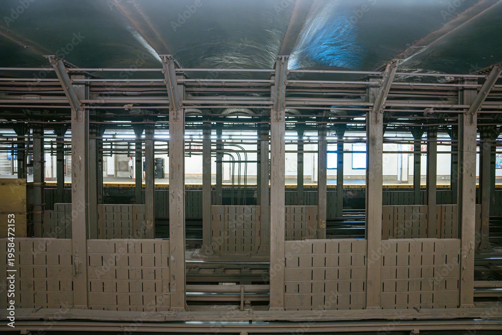 Fototapeta premium A wide view of steel beams and subway tracks inside an underground tunnel in Manhattan. The New York City metro infrastructure reveals industrial architecture and railway engineering.