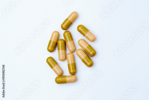 Macro close-up of multiple anthelmintic gelatin capsules scattered on white surface, pharmaceutical deworming medication concept
