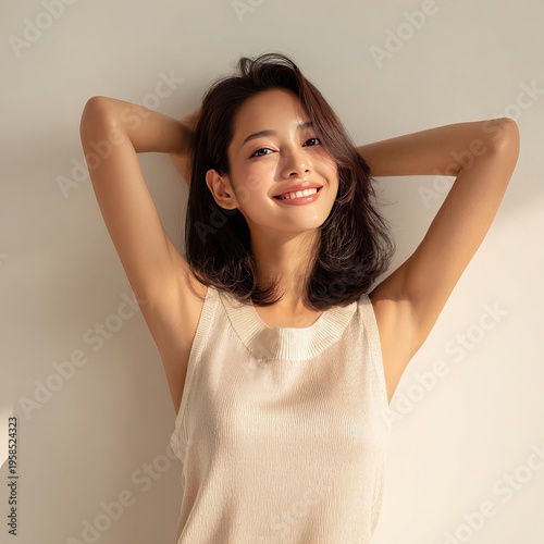 Smiling woman raising arms showing underarms in natural beauty concept,Confident young woman with raised hands and glowing skin in soft light,Natural skincare concept with woman raising arms and radia