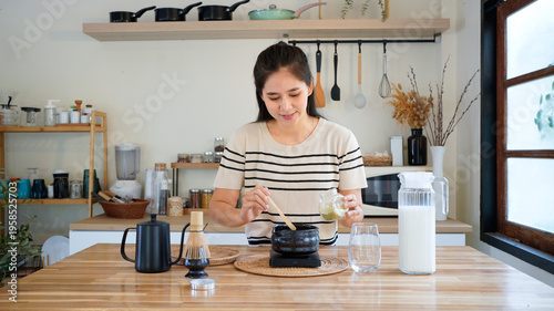 Fotografie Young Asian woman carefully scooping matcha powder into a traditional tea bowl i