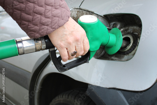 Schilderij op canvas Close-Up of Hand Holding Fuel Pump Nozzle Refueling Car at Petrol Station – Gaso