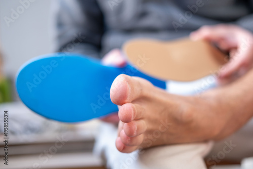 Man trying orthopedic shoe insoles on bare foot, fitting medical arch support insert, Podiatry and foot health prevention, foot care and podiatry concept, choosing comfortable support for walking