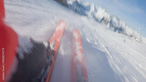 Low angle POV of skier going fast down the hill on sunny clear day . Skier own skis prominently featured in the foreground