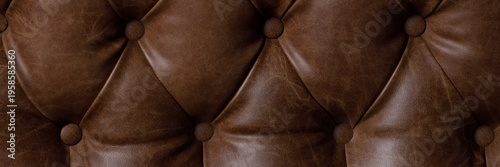 The rich texture of brown leather with a classic tufted design. Quality craftsmanship and a vintage aesthetic. Close-up.