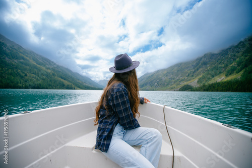 Photos Woman on boat admiring scenic mountain lake view under cloudy sky