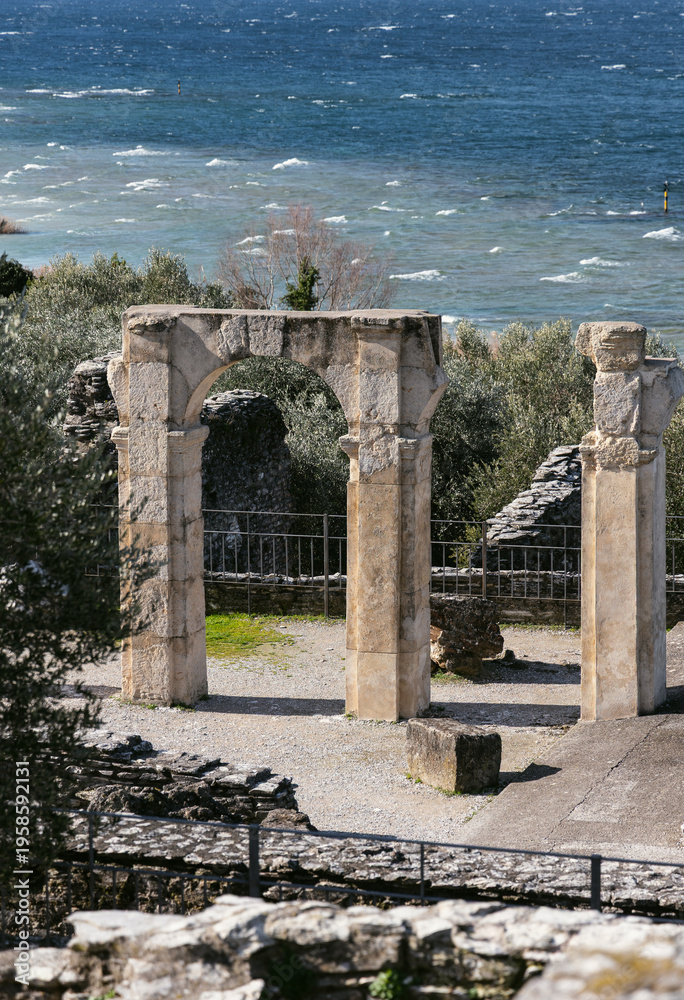 Fototapeta premium Ancient stone arch ruins near Lake Garda with turquoise water, Italy