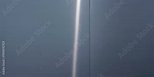 Close-up of dark brushed metal surface with a single bright vertical light streak with metal texture