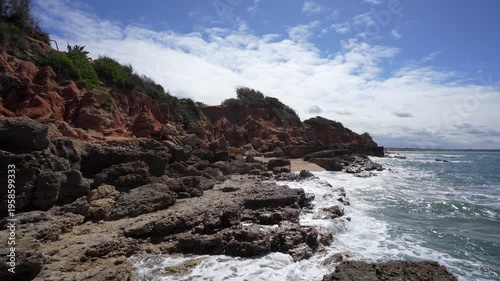 Rocky Cliffs and Sandstone Formations on the Coast of Chiclana Spain; Scenic Atlantic Ocean Waves Crashing Against Rocks at La Barrosa Beach in Andalusia with Blue Sky Establishing Shot