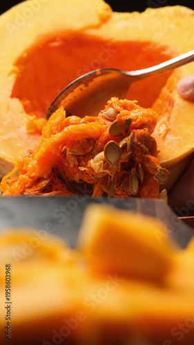 Vertical video of pumpkin cooking. Cleaning inside of pumpkin using spoon. Removing seeds and pulp from pumpkin with spoon. Orange pumpkin is healthy for body. Vegetable diet.