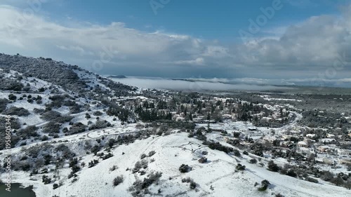 Aerial view of Merom Golan and Bental Reservoir covered in snow with wind turbines rising above the fog, Golan Heights, Israel