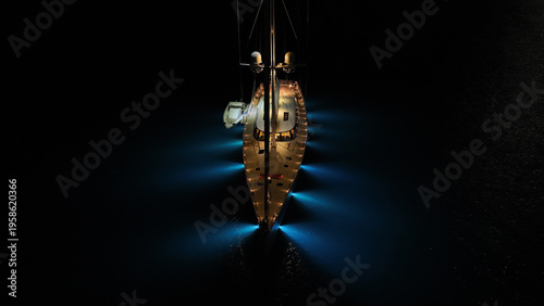 Aerial drone night shot of illuminated sail boat with wooden deck anchored in deep blue Aegan sea
