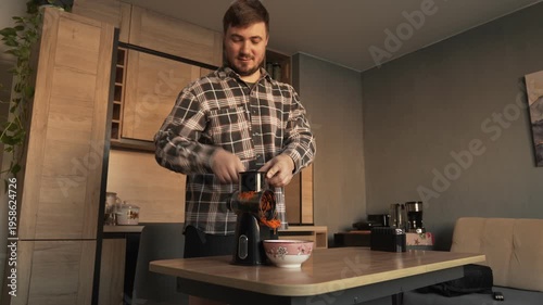 A male householder cuts carrots on a vegetable slicer
