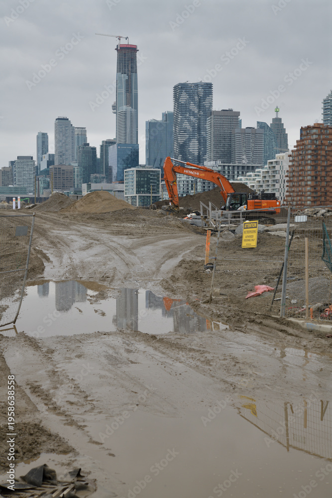 Fototapeta premium Muddy York: view of heavy machinery at development of Biidaasige Park (west of Cherry St) with view of Toronto skyline