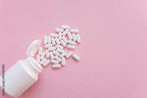White tabletts or pills on the pink background with place for text.