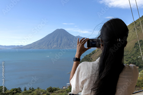 Wallpaper Mural Woman taking a photo of volcanos and mountains at lake atitlan from a restaurant patio. travel, exploration, and nature appreciation Torontodigital.ca