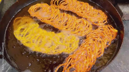 Frying Jalebi Sweets in a Large Black Pan with Golden Syrup