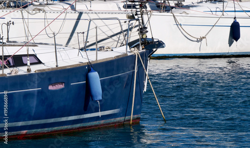 Sailing boats moored at the dock with fenders on the hull