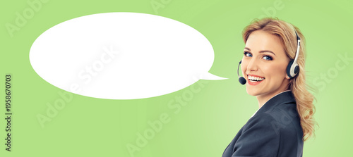 Representative call center. Blond businesswoman callcenter support phone operator wear headset, black suit, isolated soft green background. White empty mockup speech bubble. Customer service help ad
