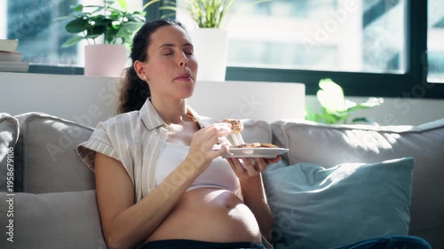 Video of pregnant woman eating a cookies sitting on the couch at home