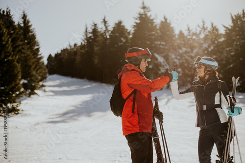 Skiers give thumbs up at the ski resort on a sunny day surrounded by trees