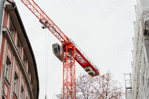 Urban construction scene featuring a historic building covered in scaffolding with a crane above, development and architectural transformation.