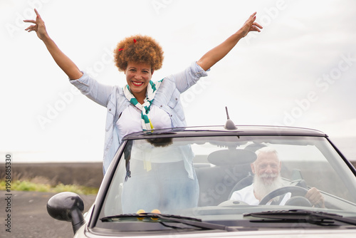 Happy elderly couple having fun together during road trip vacation with convertible car - Insurance, car rental and holiday concept