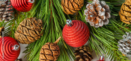 A Christmas composition. Pine and fir branches and fir cones and Christmas balls and decorations panorama. Flat lay, top view.