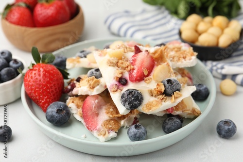 Foto Pieces of tasty yogurt bark with berries and granola on light table, closeup