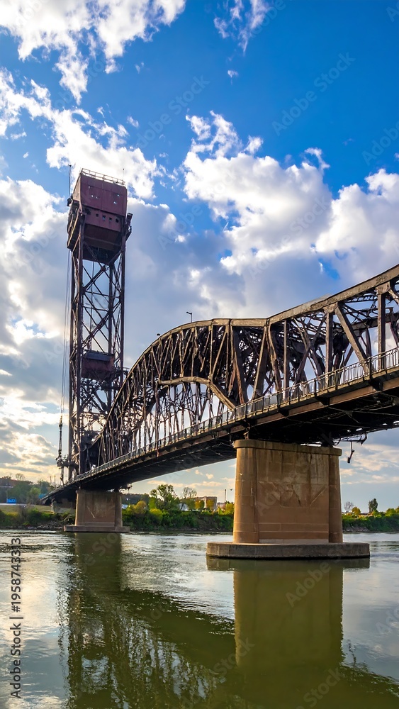 Fototapeta premium Tall drawbridge over river with clouds