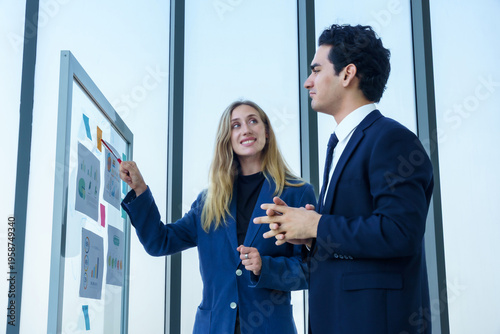 Two businessman and businesswoman partners  in suits smiling standing Talking Discussing presenting financial graph Concept on flip chart board  business expressed embolden and successful concept.