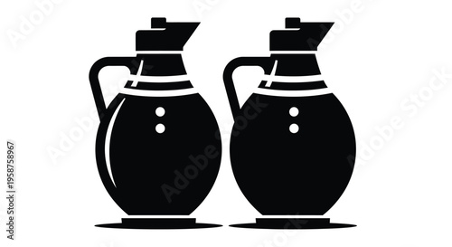 Two identical dark oil or vinegar cruets with handles and spouts are positioned closely together, suggesting a set for culinary use.