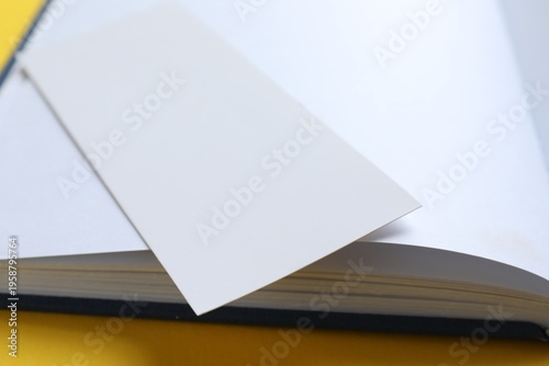 Bild auf Leinwand Book with white bookmark on yellow background, closeup