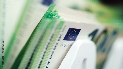 Money counting machine processing stacks of cash with visible Euro banknotes, showcasing detailed currency features and a clean, organized workspace environment