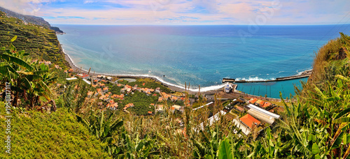 Panoramic summer view of a Madeira island coastal town from the sea with clear blue water and sky