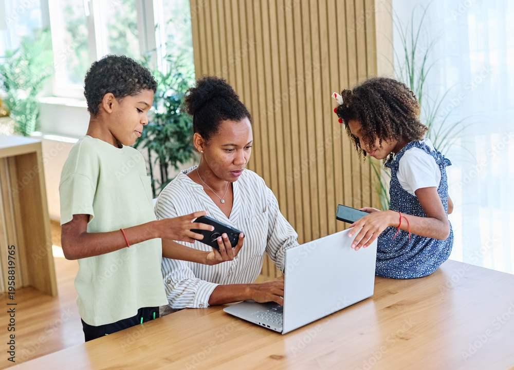 Obraz premium Portrait of ayoung businesswoman working on laptop from home distracted by surrounding noisy children. Motherhood, childhood, family, freelance job, home office concept