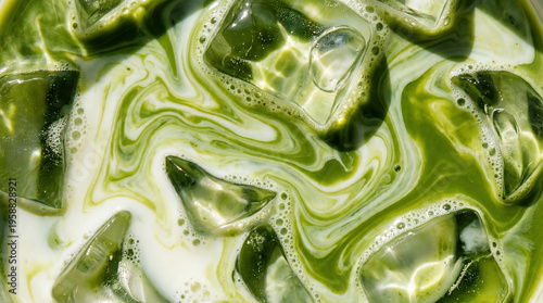 macro top-down view of iced matcha green tea latte with swirling milk and ice cubes texture background