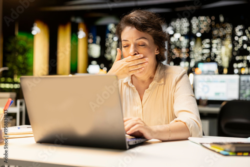 Quadro su tela Restless sleepy businesswoman yawning in the office struggling to stay awake, dealing with sleep deprivation and work tension due to overload at night