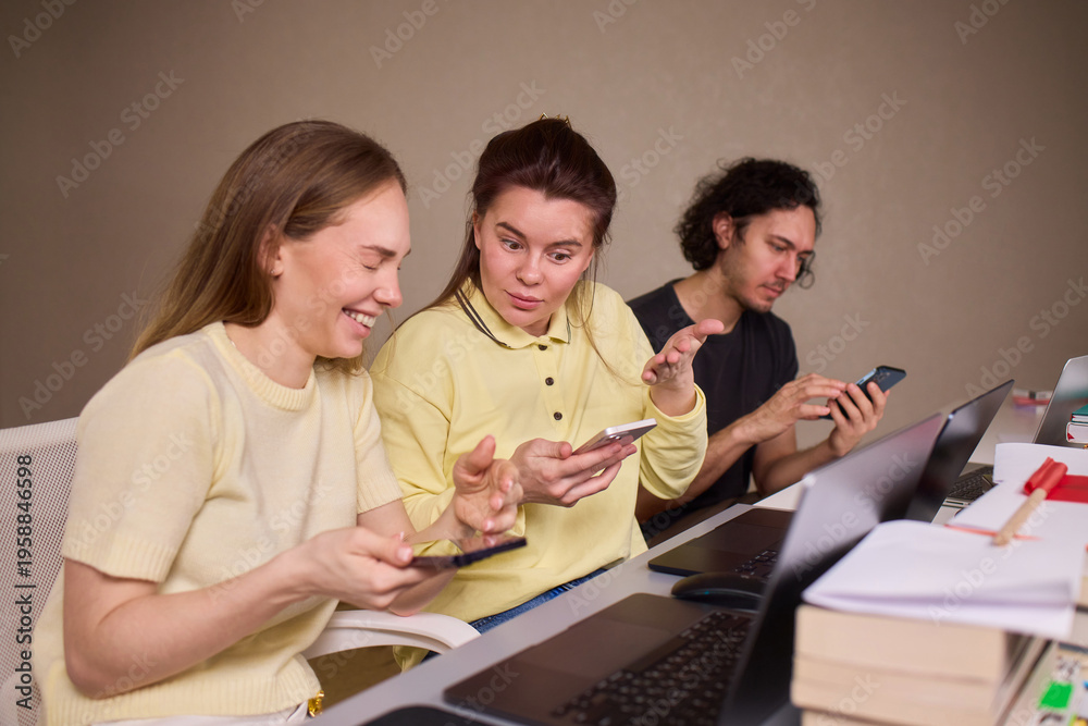 Fototapeta premium Individuals engaged in informal discussion about mobile device features. Casual indoor gathering where friends analyze smartphone screens and share opinions warmly